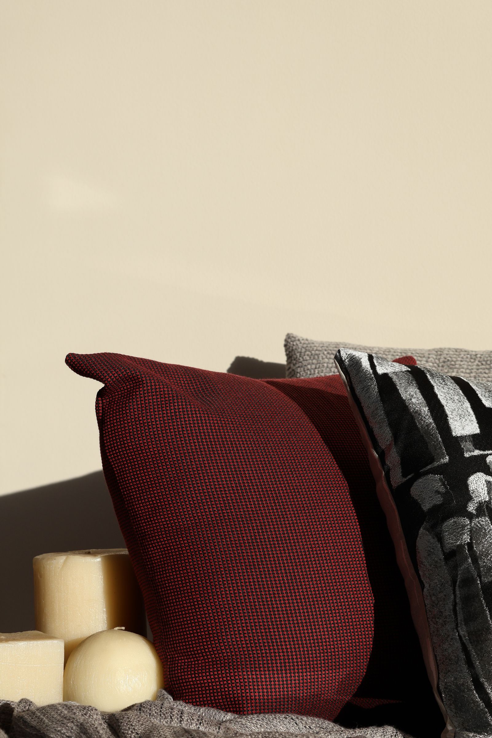 Coussins rouges et gris avec des bougies pilier sur un lit, lumière chaude